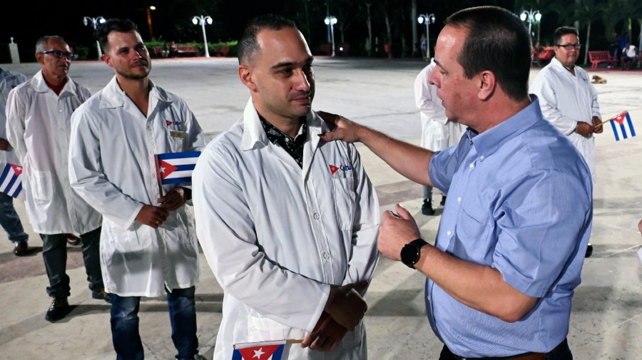 Cuban Health Minister José Ángel Portal (R) greets doctors and nurses from Cuba's Henry Reeve International Medical Brigade before they leave to Turkey to care for the victims of the earthquake, at the Central Unit of Medical Cooperation in Havana, on February 10, 2023.