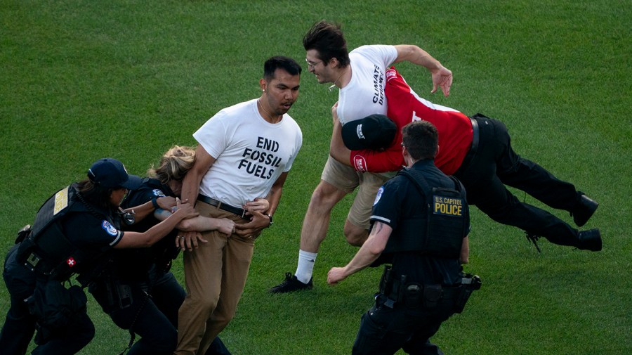 Climate protesters are tackled by U.S. Capitol Police and National security as they rush on to the field during the annual Congressional Baseball game