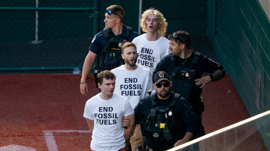 Climate protesters are escorted out by U.S. Capitol Police after running on to the field the annual Congressional Baseball game