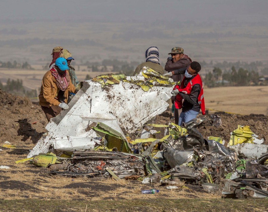 FILE - Workers recover debris at the scene of an Ethiopian Airlines Boeing Max plane crash on March 11, 2019, outside of Addis Ababa, Ethiopia. U.S. prosecutors and victims' families are waiting for Boeing to decide whether to accept a plea deal that would settle a criminal charge that the aerospace giant misled regulators who approved the 737 Max before two of the jetliners crashed in Ethiopia and Indonesia. (AP Photo/Mulugeta Ayene, File)`