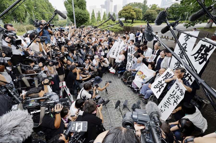 The plaintiffs, their lawyers and supporters hold the signs reading "Winning lawsuit" outside the Supreme Court after in Tokyo, Japan, Wednesday, July 3, 2024. Japan’s Supreme Court, in a landmark decision Wednesday, ordered the government to pay compensation to dozens of victims who were forcibly sterilized in the 1950s to 1970s under a now-defunct Eugenics Protection Law that was designed to eliminate offsprings of people with handicaps. (Kyodo News via AP)