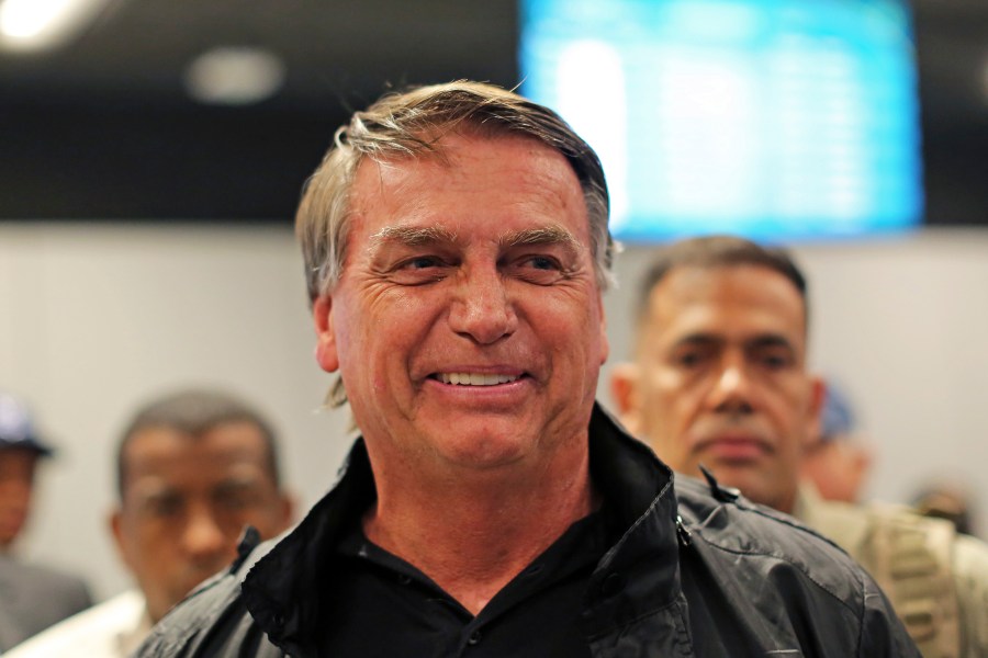 Former Brazilian President Jair Bolsonaro smiles after deplaning at the international airport in Florianopolis, Santa Catarina state, Brazil, Friday, July 5, 2024. Brazilian police have indicted Bolsonaro for money laundering and criminal association in connection with undeclared diamonds the far-right leader received from Saudi Arabia during his time in office, according to a source with knowledge of the accusations. (AP Photo/Heuler Andrey)