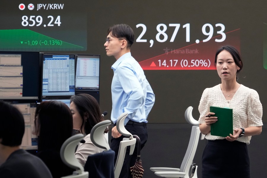 A currency trader passes by the screen showing the Korea Composite Stock Price Index (KOSPI) at the foreign exchange dealing room of the KEB Hana Bank headquarters in Seoul, South Korea, Tuesday, July 9, 2024. (AP Photo/Ahn Young-joon)