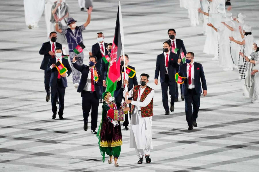 FILE - Kimia Yousofi, front left, and Farzad Mansouri, of Afghanistan, carry their country's flag during the opening ceremony in the Olympic Stadium at the 2020 Summer Olympics on July 23, 2021, in Tokyo, Japan. Afghan sprinter Yousofi is preparing to compete at her third Olympics after being selected for the Paris Games from her training base in Australia. The Australian Olympic Committee on Tuesday, July 9, 2024, congratulated Yousofi on her selection for the women's 100-meter sprint. (AP Photo/David J. Phillip, File)