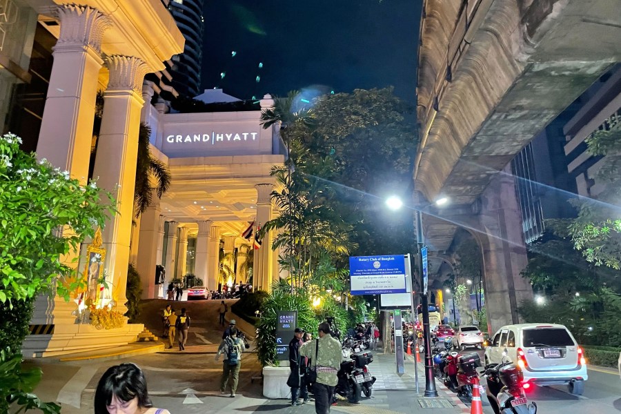 People walk outside a hotel where a number of people were found dead in Bangkok, Thailand, Tuesday, July 16, 2024. (AP Photo/Napat Kongsawad)