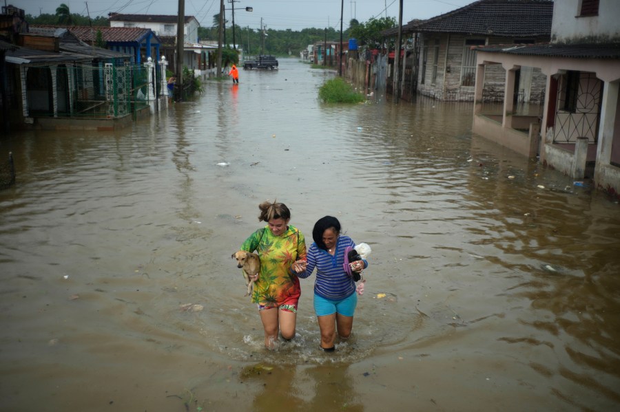 FILE - Residents wade through a street flooded by rains brought on by Hurricane Idalia, in Batabano, Cuba, Aug. 29, 2023. (AP Photo/Ramon Espinosa, File)