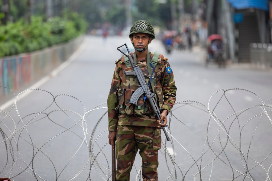 A Bangladeshi military forces soldier stands guard behind barbed wires on a main street in Dhaka, Bangladesh, Monday, July 22, 2024. Internet and mobile data services are still down despite apparent calm in Bangladesh following a verdict that scaled back a controversial quota system for government jobs after weeks of relentless protests that turned deadly. (AP Photo/Rajib Dhar)