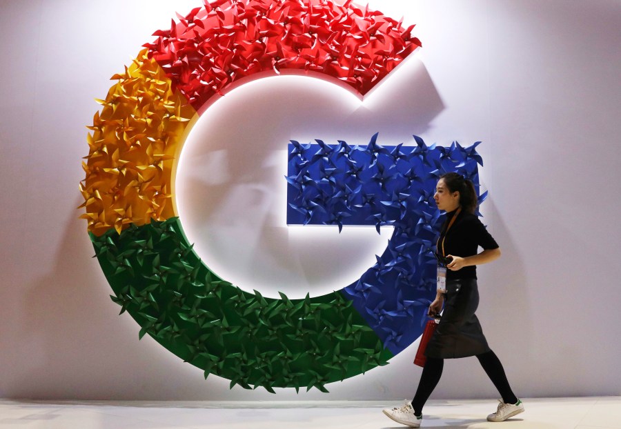 FILE - In this Nov. 5, 2018 file photo, a woman walks past the logo for Google at the China International Import Expo in Shanghai. Google is dropping plans to eliminate cookies from its Chrome web browser, making a sudden U-turn on four years of work to phase out the technology that tracks users for ad purposes. (AP Photo/Ng Han Guan, File)