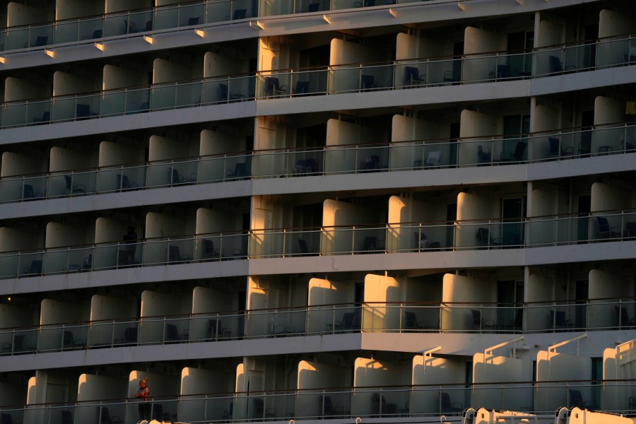 A woman, bottom left, stands on the balcony of a cruise ship which is docked at Athens' port city of Piraeus, as the sun rises on Monday, July 22, 2024. The heatwave continues in Greece, with temperatures hovering at 40 degrees Celsius (104 Fahrenheit) in several places, but the meteorologists expecting to slight drop from tomorrow. (AP Photo/Thanassis Stavrakis)