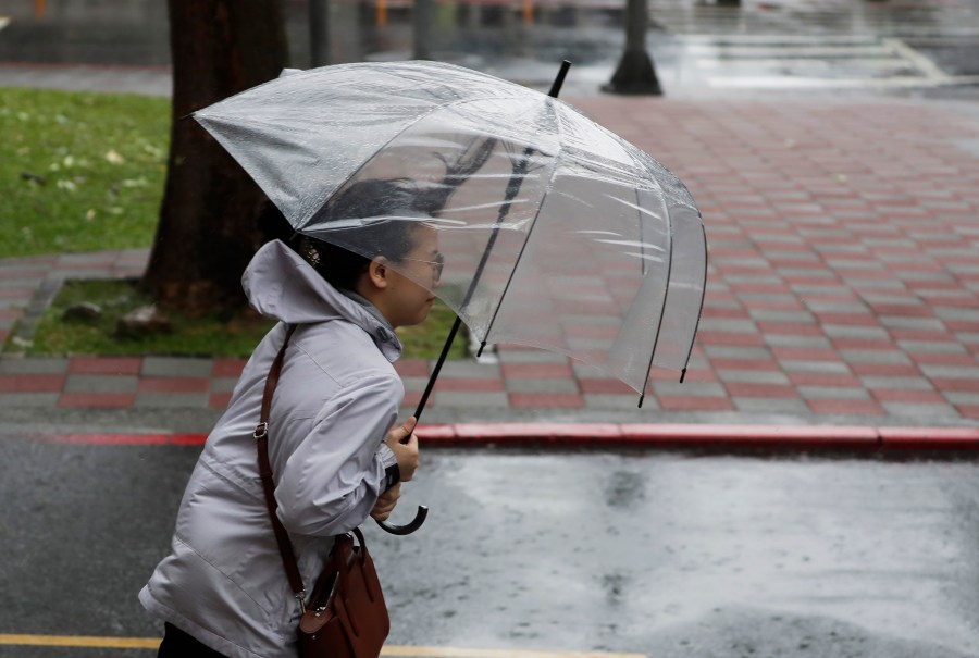 A woman struggles with her umbrella against gusts of wind generated by Typhoon Gaemi in Taipei, Taiwan, Wednesday, July 24, 2024. (AP Photo/Chiang Ying-ying)