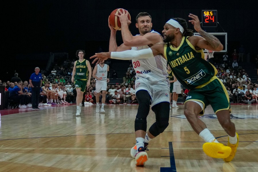 Serbia's Aleksa Avramovic, left, drives to the basket as Australia's Patty Mills tries to block him during an exhibition basketball match between Australia and Serbia at the USA Basketball Showcase, ahead of the 2024 Paris Olympic basketball tournament, in Abu Dhabi, United Arab Emirates, Tuesday, July 16, 2024. (AP Photo/Altaf Qadri)