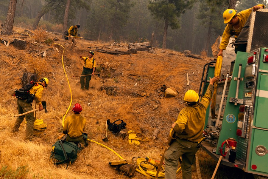 Firefighters with the United States Forest Service Lassen National Forest prepare a hoselay on a hillside during the Park fire near Paynes Creek in Tehama County, Calif., Saturday, July 27, 2024. (Stephen Lam/San Francisco Chronicle via AP)