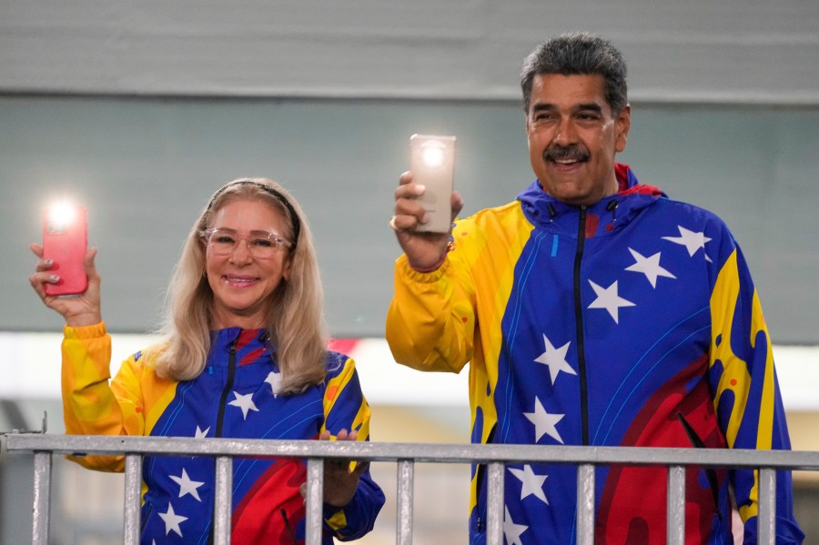 President Nicolas Maduro and First Lady Cilia Flores turn on their mobile phone flashlights after voting in the presidential elections in Caracas, Venezuela, Sunday, July 28, 2024. Maduro is seeking re-election for a third term. (AP Photo/Fernando Vergara)