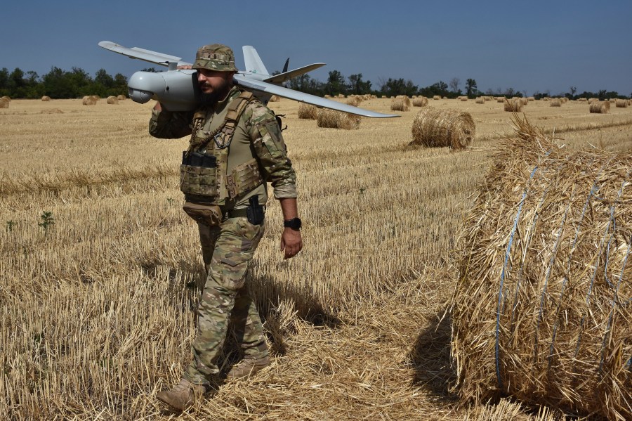 A soldier of Ukraine's National Guard 15th Brigade carries a reconnaissance drone Leleka on a wheat field to determine Russian positions near the front line in Zaporizhzhia region, Ukraine, Monday, July 29, 2024. (AP Photo/Andriy Andriyenko)