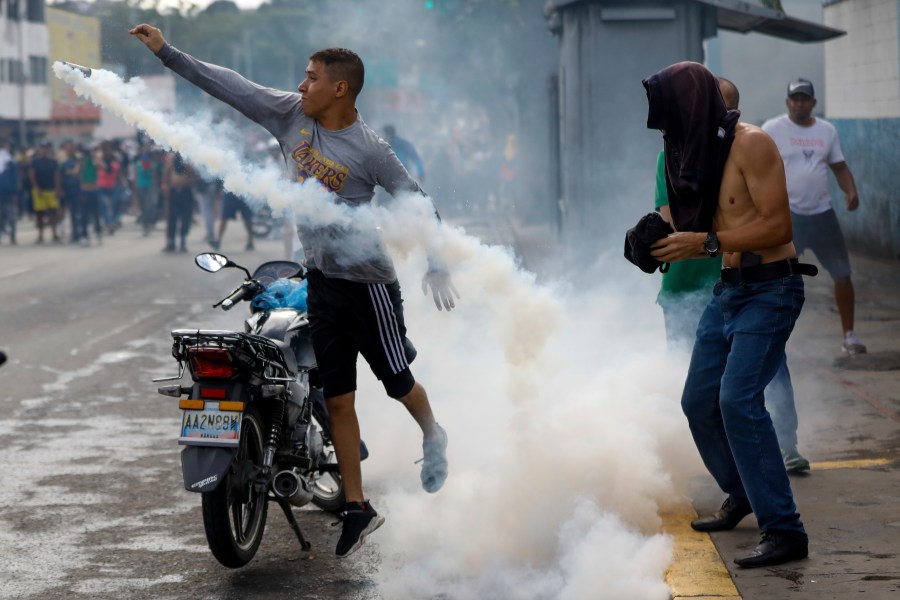 A protester throws a gas canister back at police during demonstrations against the official election results declaring President Nicolas Maduro's reelection, the day after the vote, in Caracas, Venezuela, Monday, July 29, 2024. (AP Photo/Cristian Hernandez)