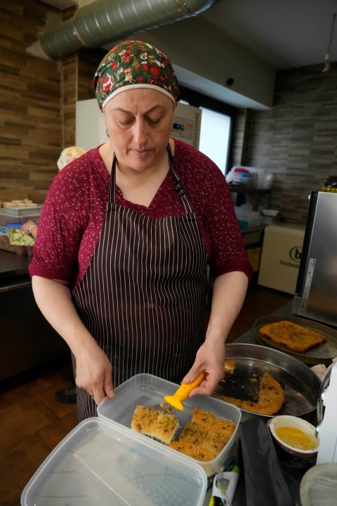 Jumana Farho, from Syria, prepares Kunafa a traditional Syrian cake in the HummusTown kitchen in Rome, Saturday, July 27, 2024. A pair of Syrians have created community that provides support to migrants and vulnerable people in Rome, by sharing the flavors of a homeland torn by civil war. Created in 2018 as a "humanitarian catering service," HummusTown originally aimed at raising funds for families and friends in Syria. (AP Photo/Gregorio Borgia)