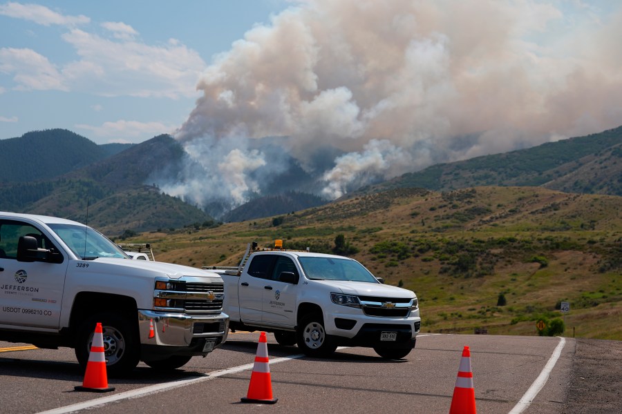 Jefferson County, Colo., vehicles block the road as smoke rises from a wildfire as it burns along a ridge near the Ken Caryl Ranch development Wednesday, July 31, 2024, southwest of Littleton, Colo. (AP Photo/David Zalubowski)