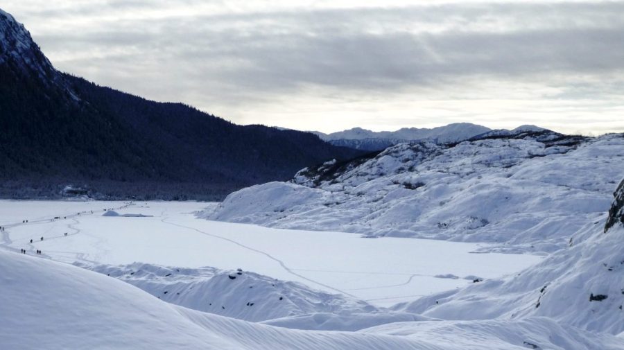 People far off in the distance are seen walking along a glacier.