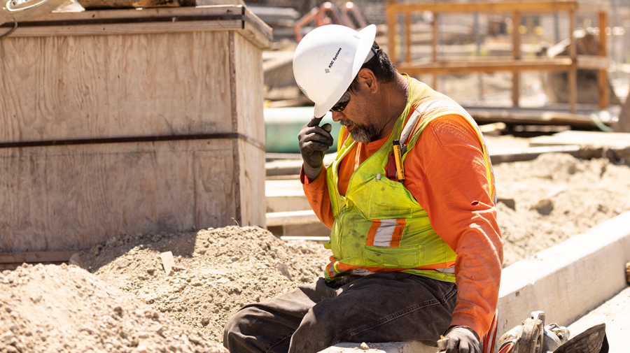 A worker adjusts his helmet on a construction site.