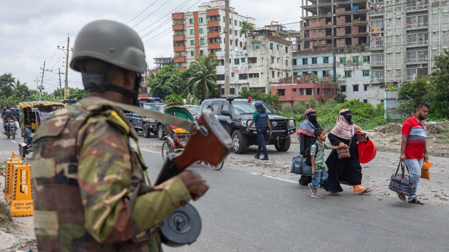 A military person stands guard as a family leaves the city on the fourth day of curfew imposed by the government amidst the countrywide deadly clashes, in Dhaka, Bangladesh, Tuesday, July 23, 2024. Internet and mobile data services are still down despite apparent calm in Bangladesh following a verdict that scaled back a controversial quota system for government jobs after weeks of relentless protests that turned deadly. (AP Photo/Rajib Dhar)