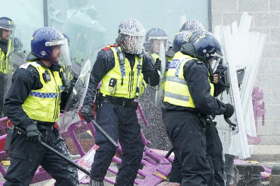 Fire extinguishers are used on police officers as trouble flares during an anti-immigration protest outside the Holiday Inn Express in Rotherham, England, Sunday Aug. 4, 2024. (Danny Lawson/PA via AP)