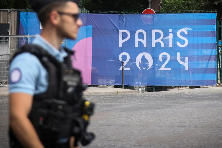 FILE - A police officer walks past a Paris Olympics canvas at the 2024 Summer Olympics, Saturday, July 20, 2024, in Paris, France. (AP Photo/Thomas Padilla, File)