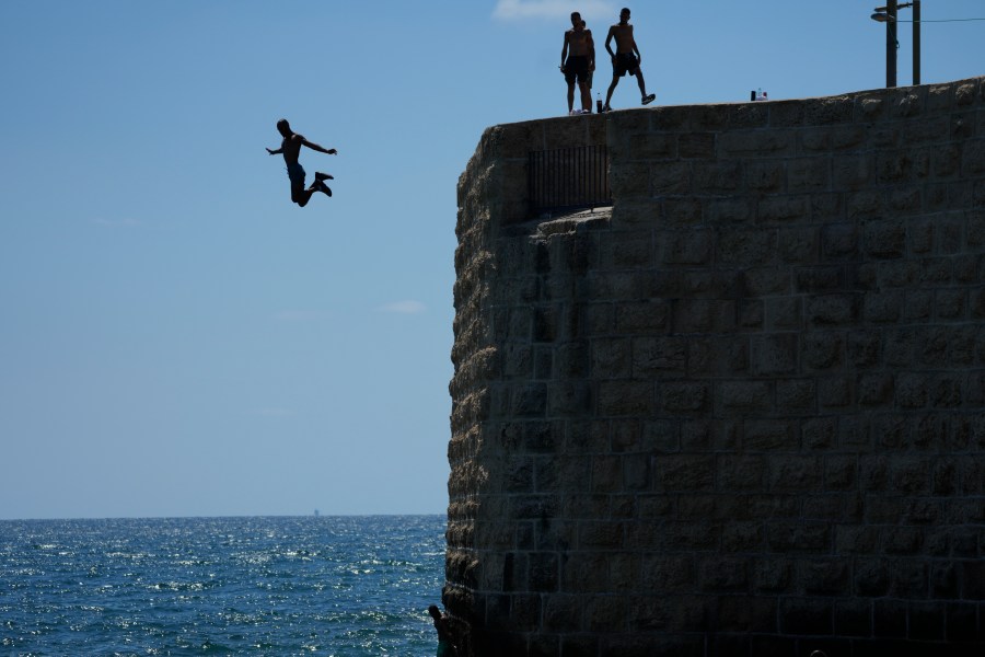 A swimmer jumps into the sea in Acre, Israel, Sunday, Aug. 4, 2024. Israel and Lebanon are the closest they have been to a full-fledged war after nearly 10 months of low-intensity cross-border exchanges. People on both sides of the border are girding for an escalation after the killings of two militant leaders in Beirut and Tehran, as worry and fatigue over a conflict with no end in sight sets in. (AP Photo/Ohad Zwigenberg)