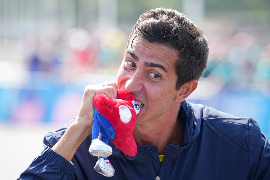 Silver medalist Brazil's Caio Bonfim pretends to bite the Paris 2024 Olympics mascot, "Phryges" at the end of the medal ceremony for the men's 20km race walk at the 2024 Summer Olympics, Thursday, Aug. 1, 2024, in Paris, France. (AP Photo/Vadim Ghirda)