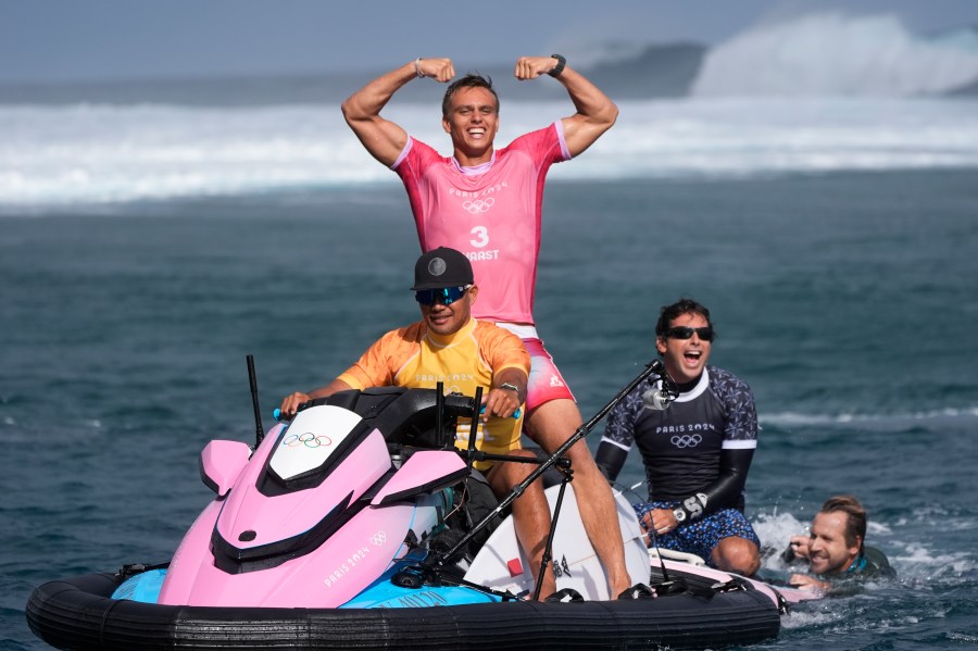 Kauli Vaast, of France, center, celebrates alongside his coach Jeremy Flores, second from right, after winning the gold medal match of the surfing competition at the 2024 Summer Olympics, Monday, Aug. 5, 2024, in Teahupo'o, Tahiti. (AP Photo/Gregory Bull)