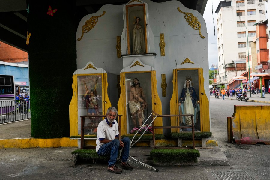 A man rests under a bridge with religious statues in the Petare neighborhood of Caracas, Venezuela, Monday, Aug. 5, 2024. (AP Photo/Matias Delacroix)