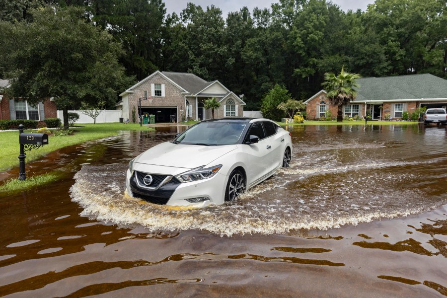 Keon Johnson leaves his house on his way to work down a street that flooded on Monday from Tropical Storm Debby and still hasn't drained, Wednesday, Aug. 7, 2024, in Pooler, Ga. (AP Photo/Stephen B. Morton)