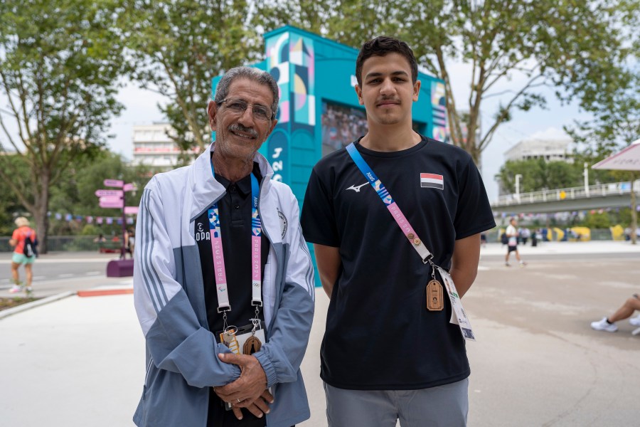 Yemeni swimmer Yusuf Marwan, right, poses for a photo with his coach ahead of his first Olympic competition, during the 2024 SUmmer Olympics, Wednesday, July 31, 2024, in Paris, France, . (AP Photo/Hanna Arhirova)