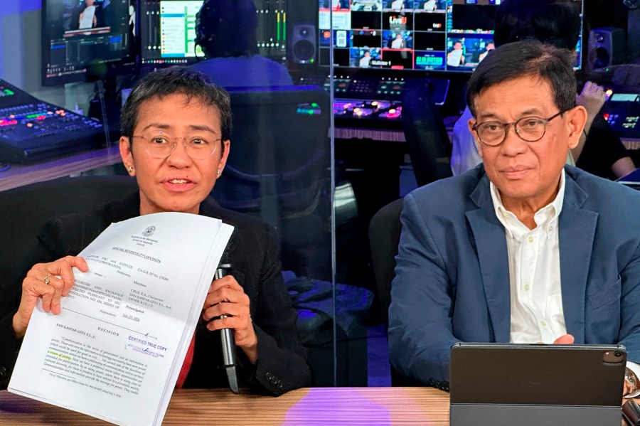 Maria Ressa, 2021 Nobel peace prize co-winner and founder of Rappler, an online news outfit, displays documents showing the court's decision, with her lawyer Francis Lim seated beside her at a press conference at the Rappler office in Manila, Philippines, Friday, Aug. 9, 2024. (AP Photo/Joeal Calupitan)