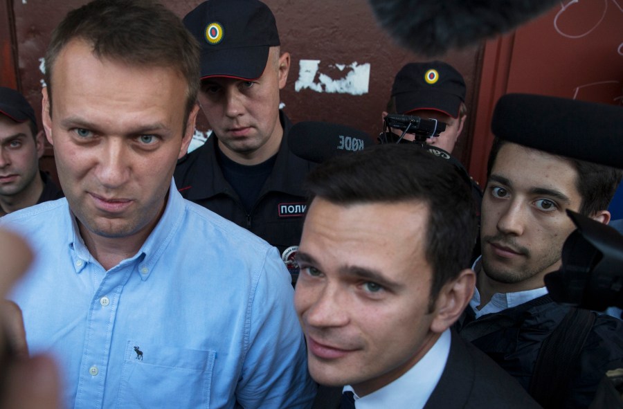 FILE - Russian opposition activist Alexei Navalny, left, and opposition candidate Ilya Yashin, center, talk as police block an entrance to the office of the Open Russia organization, founded by Russian businessman and former political prisoner Mikhail Khodorkovsky, in Kostroma, Russia, on Sept. 13, 2015. (AP Photo/ Pavel Golovkin, File)