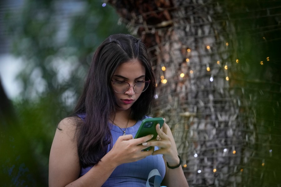 Anabel Uzcategui uses her smartphone at a plaza in Caracas, Venezuela, Friday, Aug. 9, 2024. (AP Photo/Matias Delacroix)