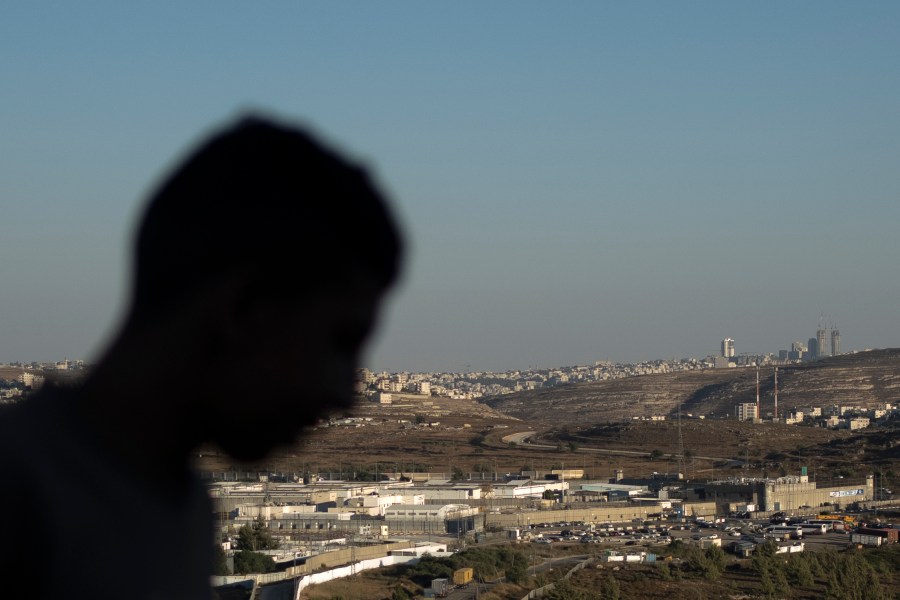 A Palestinian youth stands on a hill overlooking Israel's Ofer Prison, near the West Bank city of Ramallah, Wednesday, July 3, 2024. Five released Palestinians told The Associated Press of dramatically worsening treatment in prisons crowded with new detainees from the West Bank and Gaza over the past 10 months of war. (AP Photo/Maya Alleruzzo)