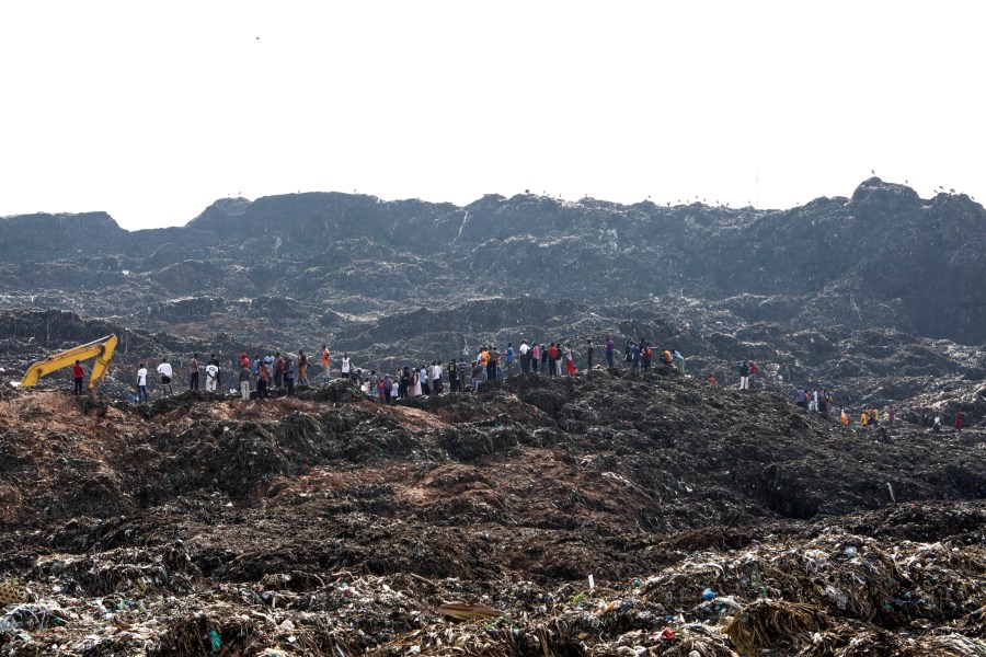 Onlookers watch as workers search for survivors at the site of a collapsed landfill in Kampala, Uganda, Sunday, Aug. 11, 2024. (AP Photo/Hajarah Nalwadda )