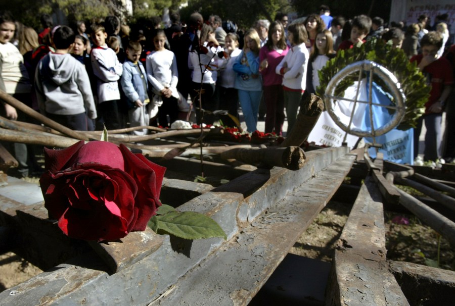 FILE -Students stand behind the wreckage of a gate at Athens Polytechnic, that was the center of an uprising in 1973 against the military dictatorship then ruling Greece, Nov. 16, 2006. (AP Photo/Petros Giannakouris, File)