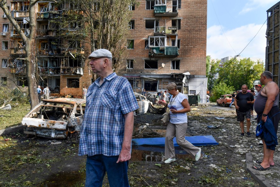 People walk near an apartment building damaged after shelling by the Ukrainian side, in Kursk, Russia, Sunday, Aug. 11, 2024. (AP Photo)