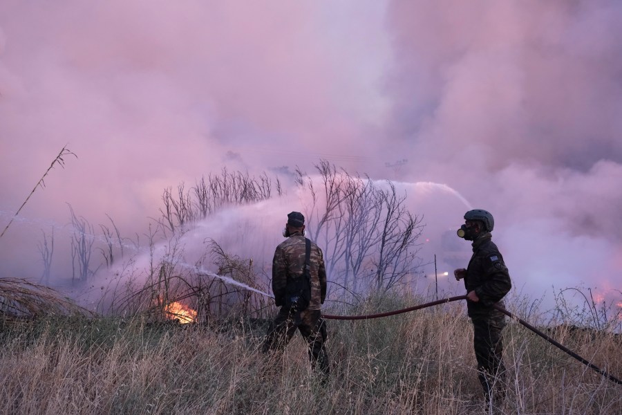 Volunteers try to extinguish the fire in northern Athens, Monday, Aug. 12, 2024, as hundreds of firefighters tackle a major wildfire raging out of control on fringes of the Greek capital. (AP Photo/Aggelos Barai)