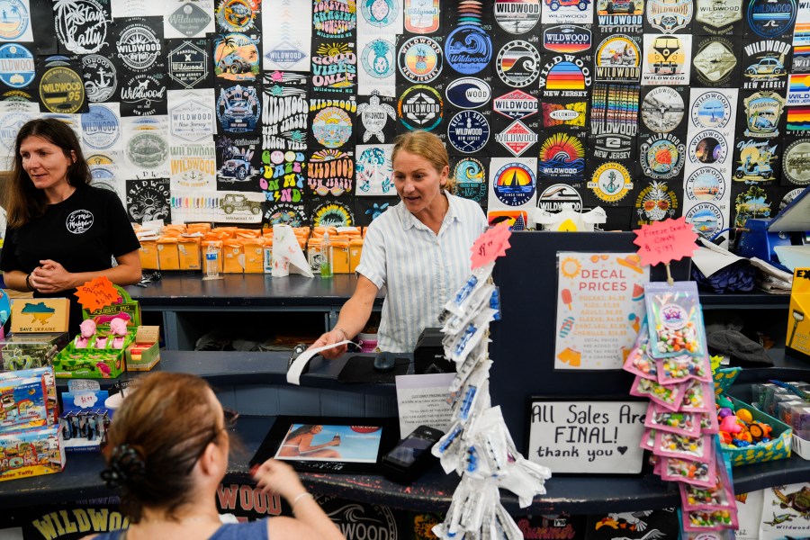 Michelle Rutkowski, owner of Boardwalk Best and Five Mile Marketplace, hands a customer a receipt in Wildwood, N.J., Friday, Aug. 9, 2024. (AP Photo/Matt Rourke)