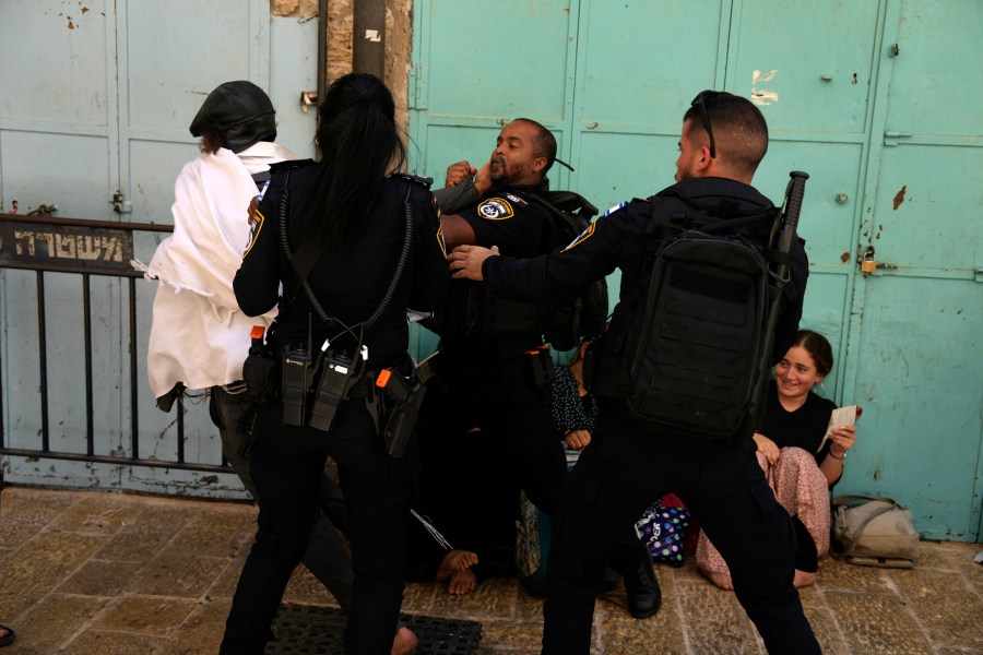 Israeli police prevent a Jewish worshipper from breaking through the police barrier to enter Jerusalem's most sensitive holy site, which Jews revere the site as the Temple Mount, believed to be the location of the First and Second Temples, and it is a holy site for Muslims as Haram al-Sharif or the Noble Sanctuary, in the Old City, Tuesday, Aug. 13, 2024 on Tisha B'Av, a day of mourning commemorating the destruction of the biblical Temples. (AP Photo/Ohad Zwigenberg)