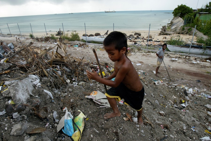 FILE - A boy scavenges for useful items at Red Beach dump on Tarawa atoll, Kiribati, on March 30, 2004. (AP Photo/Richard Vogel, File)