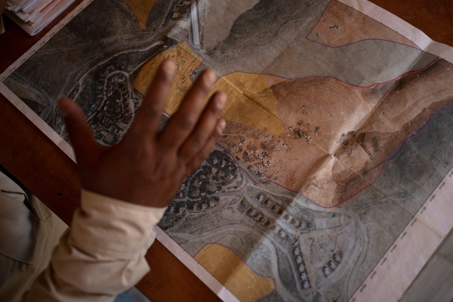 FILE - Tariq Hathaleen with a map showing the West Bank village of Umm al-Khair, top, and the Israeli settlement of Carmel on July 10, 2024. (AP Photo/Maya Alleruzzo, File)