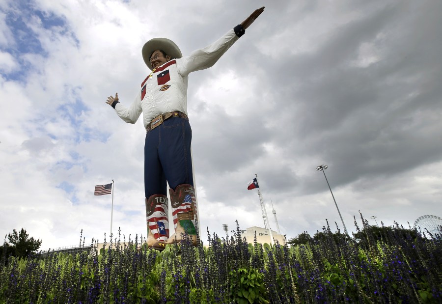 FILE - Bluebonnets, the state flower of Texas, surround Big Tex as storm clouds move in above, Friday, Sept. 27, 2013, in Dallas. (AP Photo/Tony Gutierrez, File)