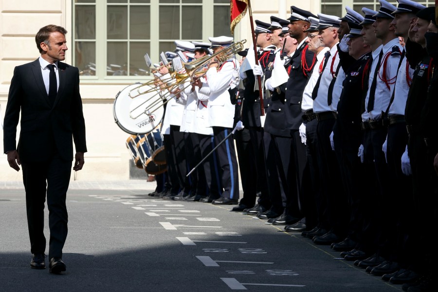 French President Emmanuel Macron reviews police officers during a ceremony to mark the 80th anniversary of the police Prefecture liberation in Paris, Monday Aug. 12, 2024. (Alain Jocard, Pool via AP)