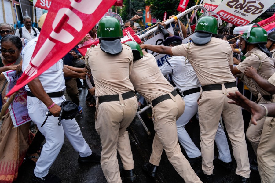 Policemen try to resist activists of Socialist Unity Center of India-Marxist (SUCI-N) from breaking a barricade during a protest against the rape and murder of a trainee doctor at a government hospital, in Kolkata, India, Friday, Aug. 16, 2024. (AP Photo/Bikas Das)