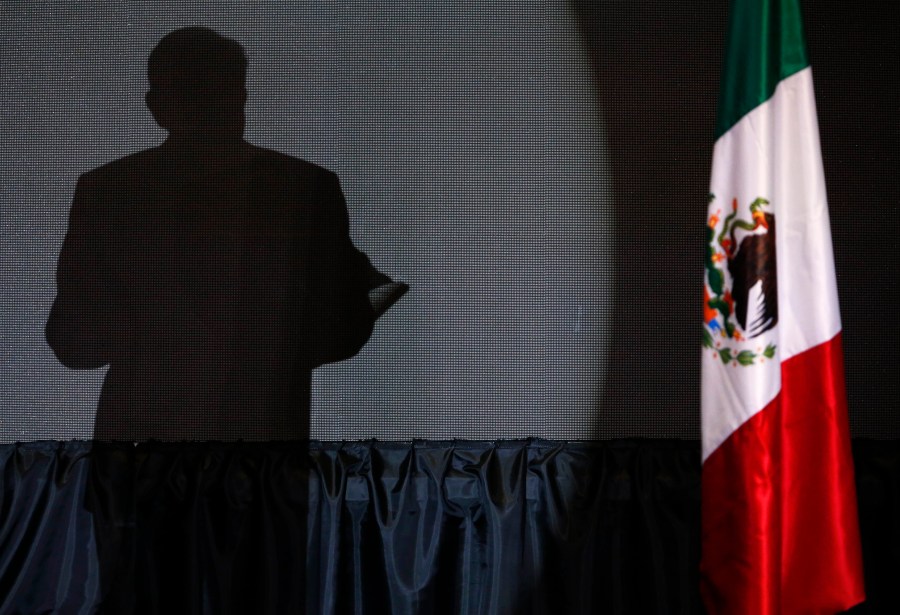 FILE - The shadow of presidential candidate Andres Manuel Lopez Obrador, founder of the ruling party, Morena, is cast on a screen as he gives his first victory speech at his campaign headquarters at the Hilton hotel in Mexico City, late July 1, 2018. (AP Photo/Marco Ugarte, File)