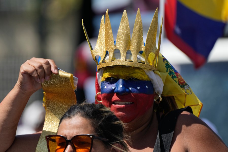 A woman, her face painted with Venezuela's national colors, rides on the back of a motorcycle during a rally to protest official results that declared President Nicolas Maduro the winner of the July presidential election, in Caracas, Venezuela, Saturday, Aug. 17, 2024. (AP Photo/Ariana Cubillos)