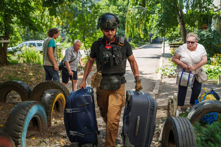 A volunteer on East SOS helps to carry bags of evacuees in Selidove, Donetsk region, Ukraine, Monday, August 19, 2024. Due to the advance of Russian troops, the war affects more and more new settlements to the west of the Donetsk region. Intensive shelling forced people to leave homes. (AP Photo/Evgeniy Maloletka)